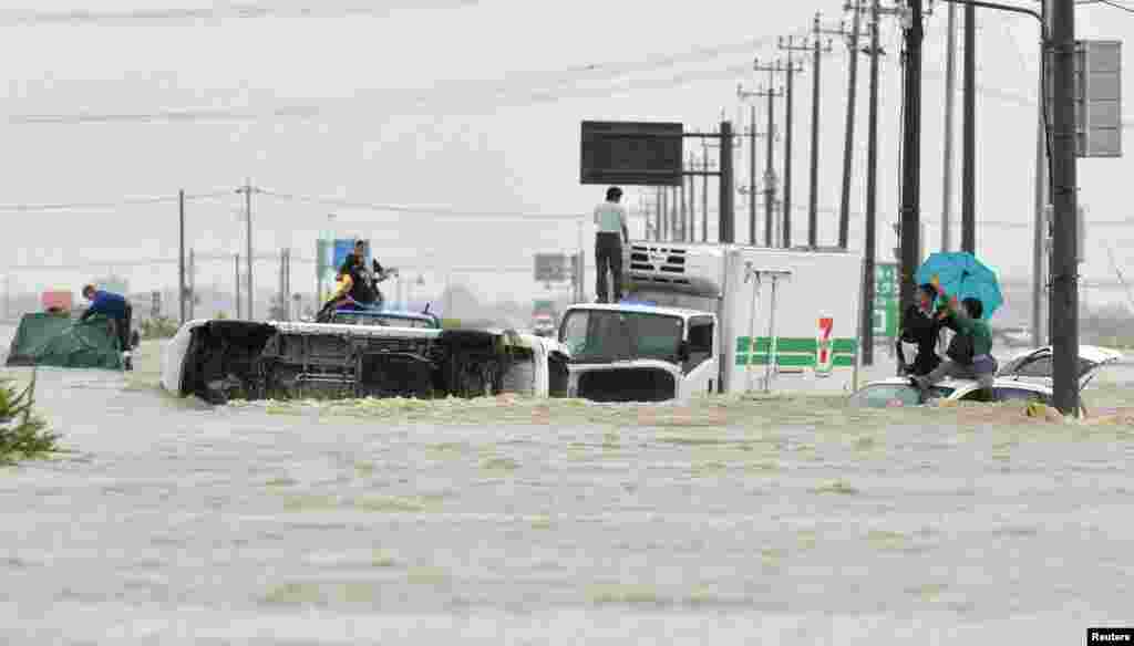People are stranded on a road flooded by the Kinugawa river, caused by typhoon Etau in Joso, Ibaraki prefecture, Japan, in this photo taken by Kyodo. Japan evacuated about 100,000 people from their homes, after rare torrential rains unleashed floods that left at least two people missing and stranded many more when rivers surged over their banks.