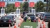 Petugas lalu-lintas mengarahkan mobil-mobil melalui lantatur (drive-through) tes Covid-19 di Stadion Dodgers, Los Angeles, California, 15 Juli 2020. (Foto: AFP)