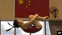 A young gymnast trains near the Chinese national flag at the Xuhui Sports School in Shanghai, China, June 16, 2016.
