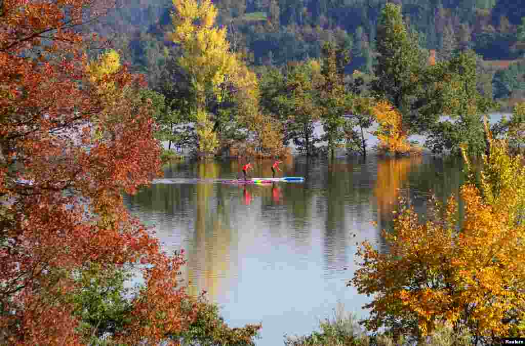 Dua orang mengayuh papan selancar di sebuah danau di kota Planina, Slovenia.