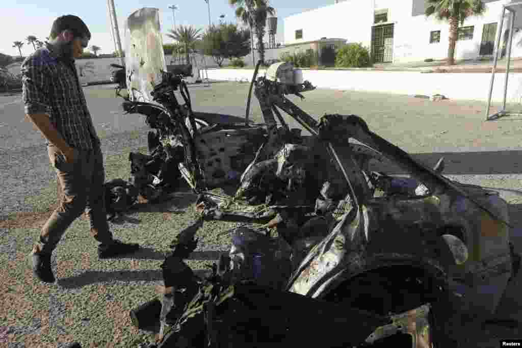A military personnel examines a car, which exploded near a women's police academy, in Tripoli August 19, 2012. Two explosions struck the Libyan capital of Tripoli on Sunday, one near the Interior Ministry and the second near a women's police academy, a Li