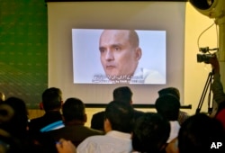 FILE - Journalists look a image of Indian naval officer Kulbhushan Jadhav, who was arrested in March 2016, during a press conference by Pakistan's army spokesman and the Information Minister, in Islamabad, Pakistan, March 29, 2016.