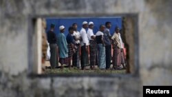 Rohingya migrants who arrived in Indonesia last week by boat are seen through the window of an abandoned building as they wait in line for breakfast at a temporary shelter in Aceh Timur regency near Langsa in Indonesia's Aceh Province, May 27, 2015.