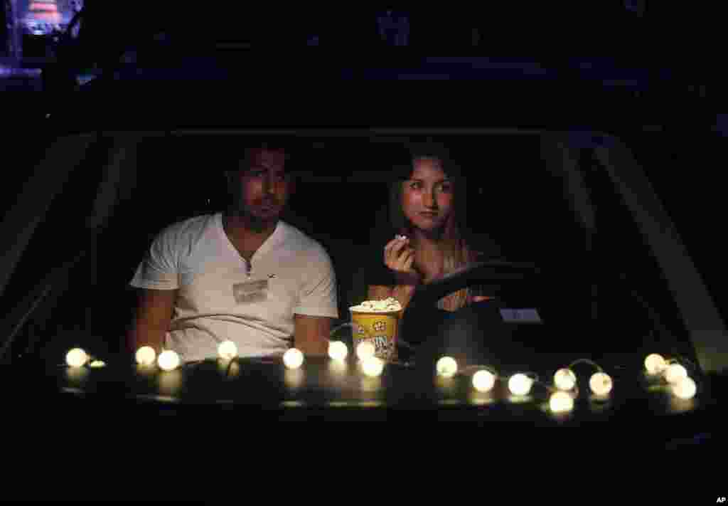 A couple sit on their car watch "Hours" at a drive-in movie event at a park, in Byblos town, north of Beirut, Lebanon, Friday, July 17, 2020. (AP Photo/Hussein Malla)