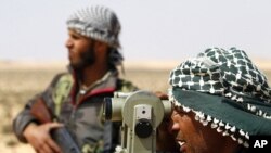 A rebel fighter surveys a sight on the road to the east of Brega in Libya, April 3, 2011