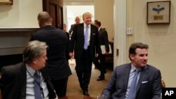 President Donald Trump smiles as he walks in from the Oval Office of the White House in Washington, Monday, Jan. 23, 2017, to host breakfast with business leaders in the Roosevelt Room. Sitting at the table are White House Senior Adviser Steve Bannon, left, and Kevin Plank, founder, CEO and Chairman of Under Armour. (AP Photo/Pablo Martinez Monsivais)