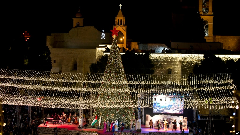 Palestinian Christians celebrate the lighting of a Christmas tree outside the Church of the Nativity, traditionally believed by Christians to be the birthplace of Jesus Christ in the West Bank city of Bethlehem, Saturday, Nov. 30, 2019. (AP Photo/Majdi Mo