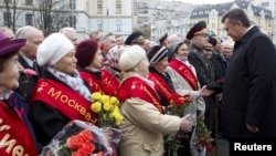 Ukrainian President Viktor Yanukovich (R) greets veterans during a ceremony to mark the day of Ukraine's liberation from Nazi invaders during World War II on the day of the parliamentary elections in Kiev, October 28, 2012.