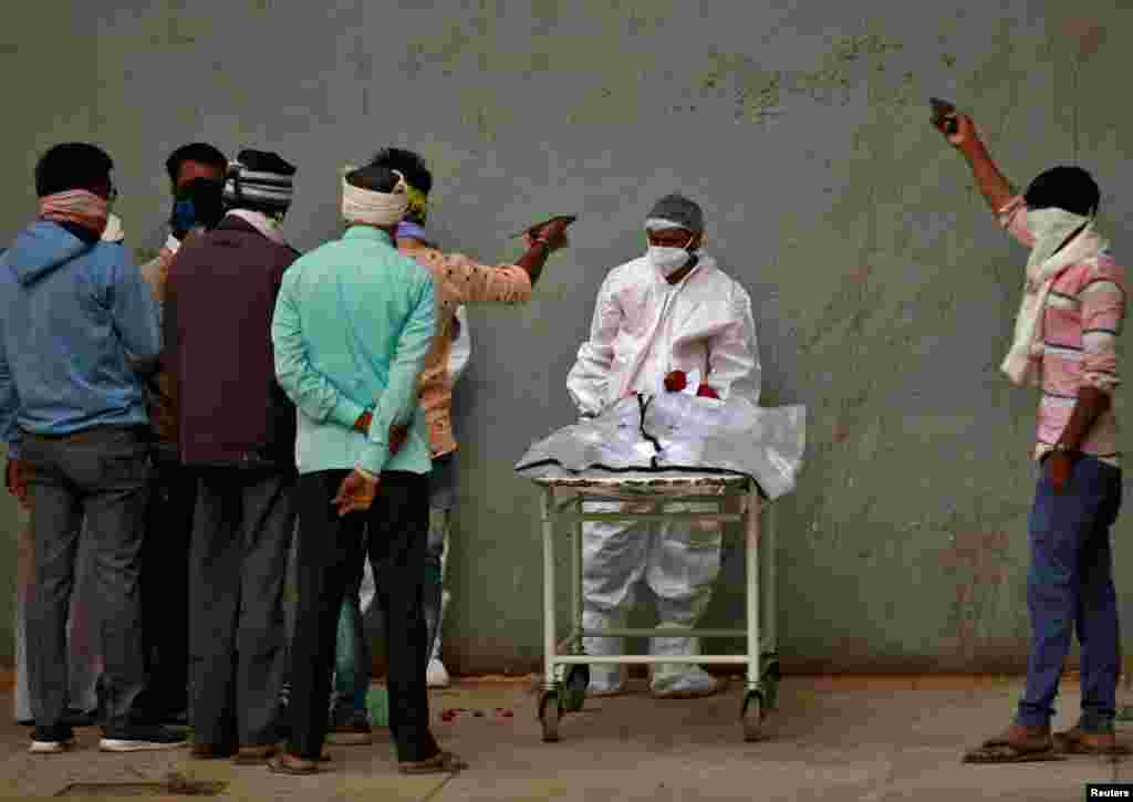 Men take photographs of the body of their relative after he died from the COVID-19 at a hospital in Ahmedabad, India.