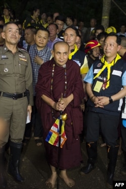 Buddhist monk Kruba Boonchum, center, exits after praying with relatives of the missing children in Tham Luang cave during a rescue operation, July 4, 2018.