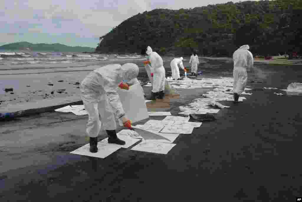 Los trabajadores usan diferentes tipos de contenedores para eliminar el petróleo que retiran de la playa de Prao Bay en la isla Samet en Tailandia.