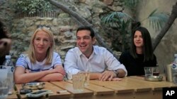 Syriza left-wing party leader and former Prime Minister Alexis Tsipras, centre, laughs as he meets with young people at a coffee shop, in central Athens, Sept. 19, 2015, ahead of Sunday, Sept. 20, 2015 elections. 