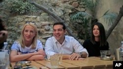 Syriza left-wing party leader and former Prime Minister Alexis Tsipras, center, laughs as he meets with young people at a coffee shop in central Athens, Sept. 19, 2015. 