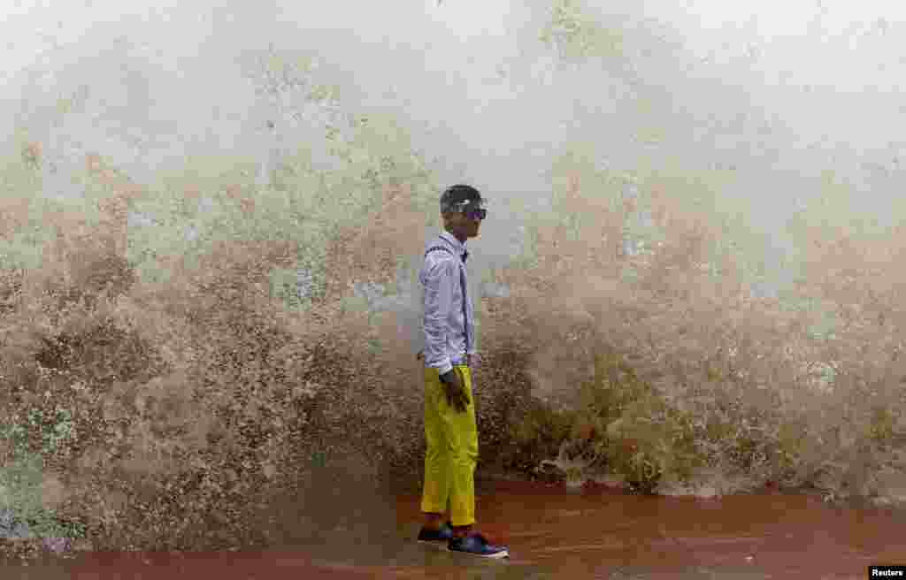 A boy poses for a photograph during a high tide in Mumbai, India.