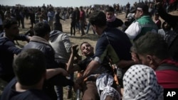 Palestinian protesters carry a wounded man from during a protest at the Gaza Strip's border with Israel, Friday, April 6, 2018.