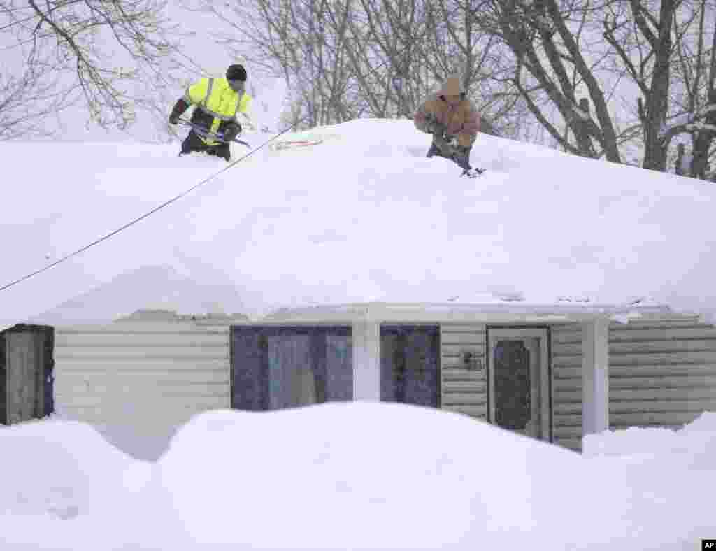 Mark Settlemyer, à gauche, est aidé par son ami à déblayer la neige du toit de la maison de sa mère de Ken Wesley, mercredi 19 novembre 2014, à Lancaster, New York.