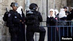 A Palestinian woman looks on as Israeli policemen prevent people from entering the compound which houses al-Aqsa mosque in Jerusalem's Old City April 16, 2014.