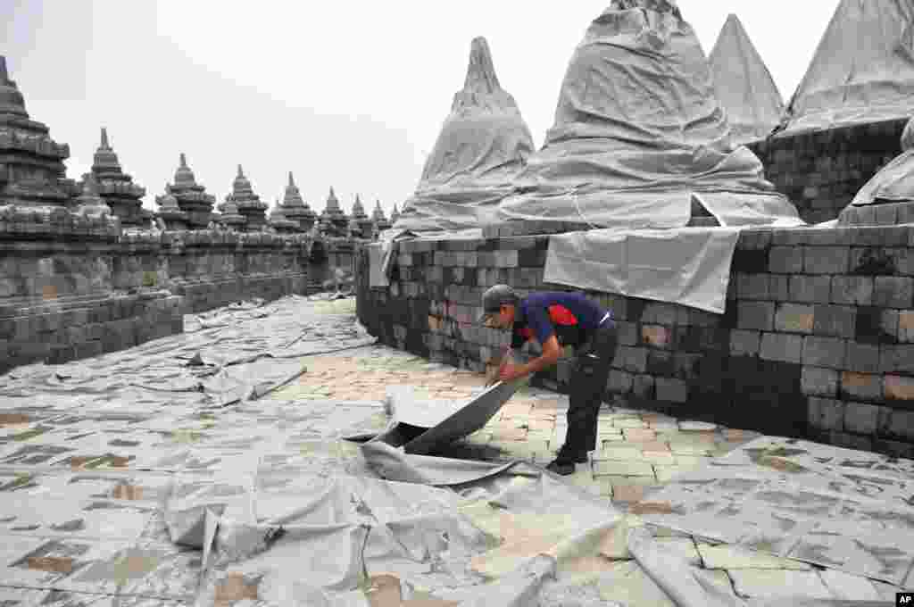 Công nhân dùng một tấm bạt để che đền Phật giáo Borobudur khỏi tro bụi từ vụ phun trào của núi lửa Kelud ở miền trung đảo Java, Indonesia, ngày 14/2/2014.