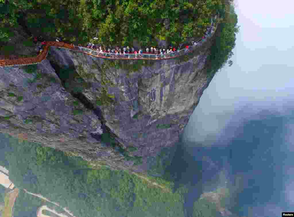 مردم در حال گذشتن از پل کنار یک کوه در ولایت هونان چین.