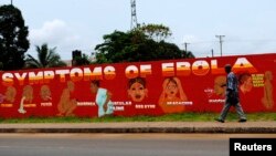 A man walks by a mural that reads "Symptoms of Ebola" in Monrovia, Liberia, Oct. 12, 2014.