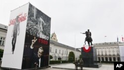 Pictures of Lech Walesa leading the 1980 strike that gave rise to the Solidarity freedom movement, top and of Prime Minister Tadeusz Mazowiecki flashing a v-sign in 1989, bottom on display in front of the Presidential Palace in Warsaw, Poland, June 2,