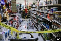 An employee walks past a damaged aisle at Anchorage True Value hardware store after an earthquake, Nov. 30, 2018, in Anchorage, Alaska.