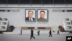 FILE - People walk past portraits of the late North Korean leaders Kim Il Sung and Kim Jong Il at Kim Il Sung Square in Pyongyang, North Korea.