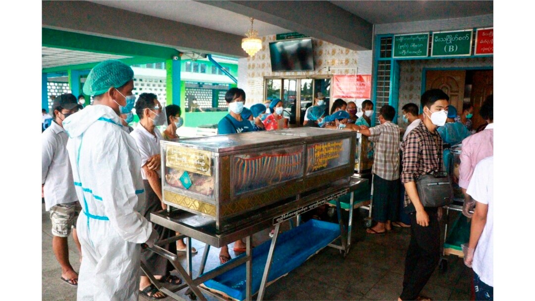 Warga mengenakan masker saat menunggu di sebelah peti jenazah yang akan dikremasi, di luar krematorium di pemakaman Yay Way, Yangon, Myanmar, 14 Juli 2021. (AP)