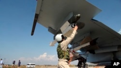 In this photo taken on Oct. 5, 2015, a Russian pilot fixes an air-to-air missile at his Su-30 jet fighter before a take off at Hmeimim airbase in Syria.