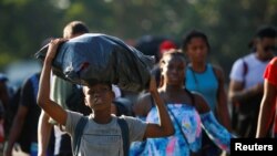 Frandlinson, 11, yang tergabung dengan kelompok migran dari Haiti, membawa barang bawaannya di kepalanya dalam perjalanan bersama migran lainnya di dekat Tapachula, Meksiko, pada 26 November 2021. Rombongan migran tersebut bergerak menuju AS. (Foto: Reuters/Jose Luis Gonzalez)