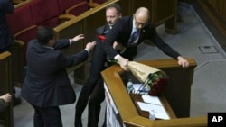Oleh Barna, a Ukrainian lawmaker from the Block of Petro Poroshenko, second left, tries pull Ukrainian Prime Minister Arseniy Yatsenuk out from the podium during his speech at a parliamentary session in the Parliament in Kyiv, Ukraine, Friday Dec. 11, 2015.
