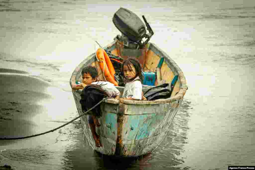Children remain on a boat, after crude oil reached the Coca River in Puerto Maderos, Sucumbios province, Ecuador, Feb. 1, 2022.&nbsp;An oil spill caused by a ruptured pipeline in Ecuador&#39;s Amazon region leaked almost 6,300 barrels into an environmental reserve, according to the company that owns the conduit.&nbsp;