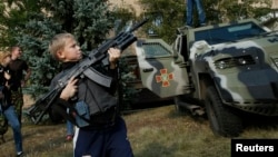 Un muchacho juega con un fusil de asalto Kalashnikov en Soledar, al este de Ucrania. 