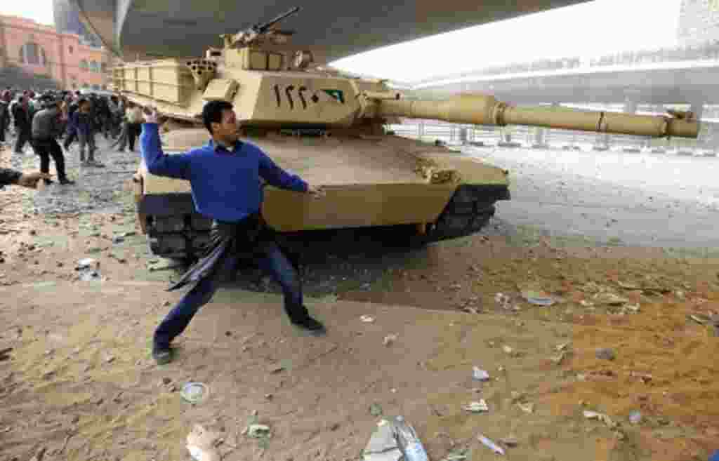 Un miembro de la oposición arroja piedras frente a un tanque durante los disturbios en favor a Mubarak.
