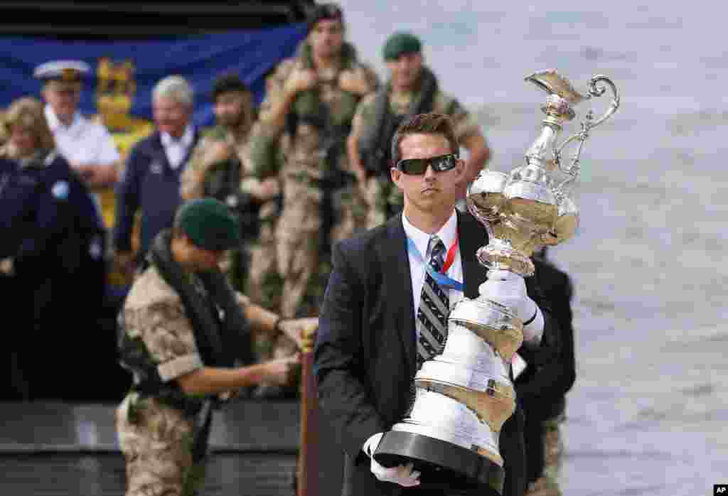 The America&#39;s Cup Trophy is carried from a Royal Marine landing craft after it arrived at the waterfront festival area in Portsmouth, England.