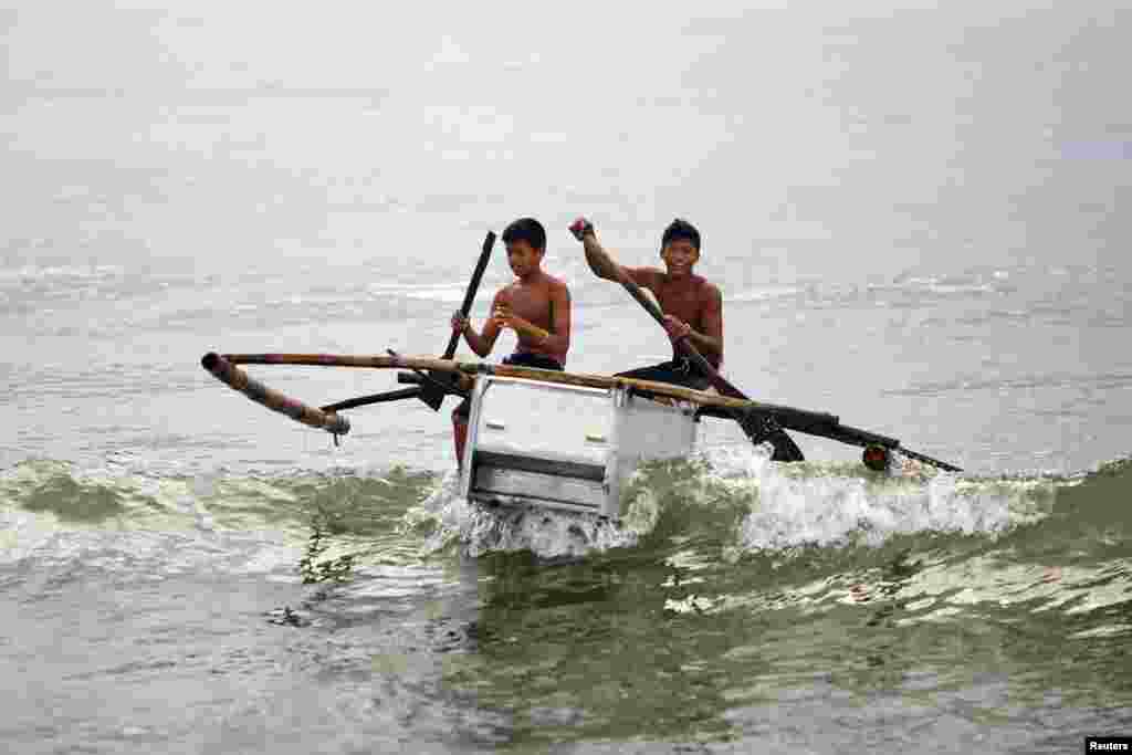 Boys maneuver their boat, made from a broken fridge and bamboo, to the beach in Tanauan, Philippines. After losing their boats and houses in the Typhoon Haiyan, fishermen of a destroyed village in Tanauan started building two-seated boats made of abandoned refrigerators and some wood.