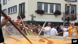 Cooks and volunteers stir eggs on an oversize pan at the 22nd Giant Omelet event in Malmedy, Belgium, August 15, 2017. (AP Photo/Daniela Berretta)