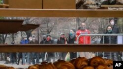 People wearing masks gather to form a "bread" line at Bread Alone outdoor market, while maintaining social distancing requirements during the COVID-19 outbreak April 4, 2020 in New York. (AP Photo/Bebeto Matthews)
