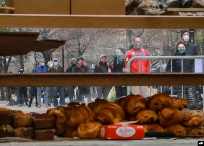 People wearing masks gather to form a "bread" line at Bread Alone outdoor market, while maintaining social distancing requirements during the COVID-19 outbreak April 4, 2020 in New York. (AP Photo/Bebeto Matthews)