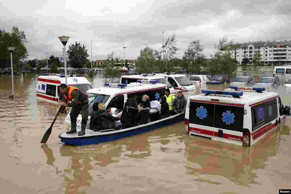 Seorang pria mendayung perahu melewati mobil ambulans yang terendam banjir di Obrenovac, barat daya Belgrad, Serbia (17/5).&nbsp;(Reuters/Marko Djurica)