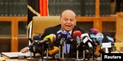 FILE - Yemen's President Abd-Rabbu Mansour Hadi speaks as he holds an agreement signed by the government and Houthi rebels, in Sanaa, Sept. 21, 2014.