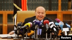 FILE - Yemen's President Abd-Rabbu Mansour Hadi speaks as he holds an agreement (L) signed between the government and Houthi rebels, in Sanaa, Sept. 21, 2014.