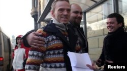 Greenpeace ship Arctic Sunrise crew member Mannes Ubels (L, front) holds papers certifying the termination of prosecution after he walked out of the offices of the Federal Migration Service Department in St. Petersburg, Dec. 25, 2013. 