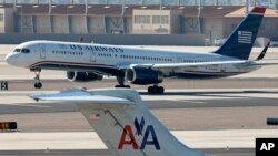 FILE - A U.S. Airways jet passes an American Airlines jet at Sky Harbor International Airport in Phoenix, Arizona, Feb. 14, 2013.