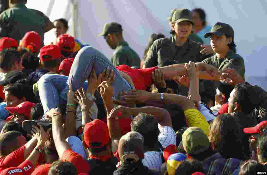 A supporter of Venezuela&#39;s late President Hugo Chavez is lifted out of the crowd after fainting while waiting for a chance to view his body in state at the military academy in Caracas, March 8, 2013. 