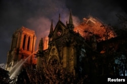 Sparks fill the air as Paris Fire brigade members spray water to extinguish flames as the Notre Dame Cathedral burns in Paris, April 15, 2019.