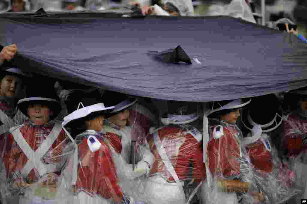 'Tamborilleros' wearing their uniform shelter from the rain, march in the traditional ' La Tamborrada', during 'El Dia Grande', the main day of San Sebastian feasts, in the Basque city of San Sebastian, northern Spain.