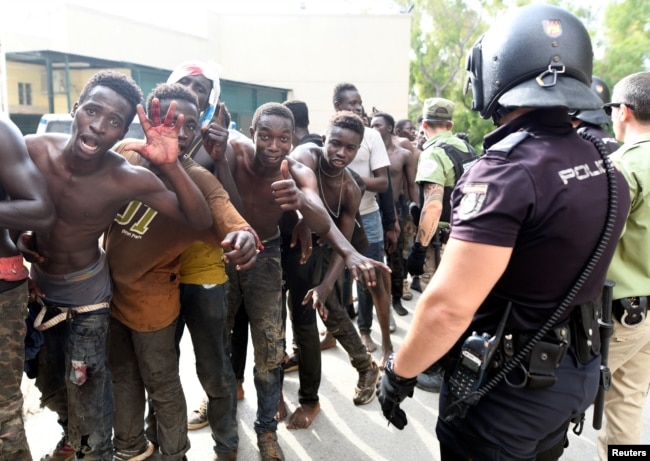 African immigrants celebrate as they enter the immigrant center CETI in the Spanish enclave Ceuta, after some 200 refugees crossed the border fence between Morocco and Ceuta, Aug. 22, 2018