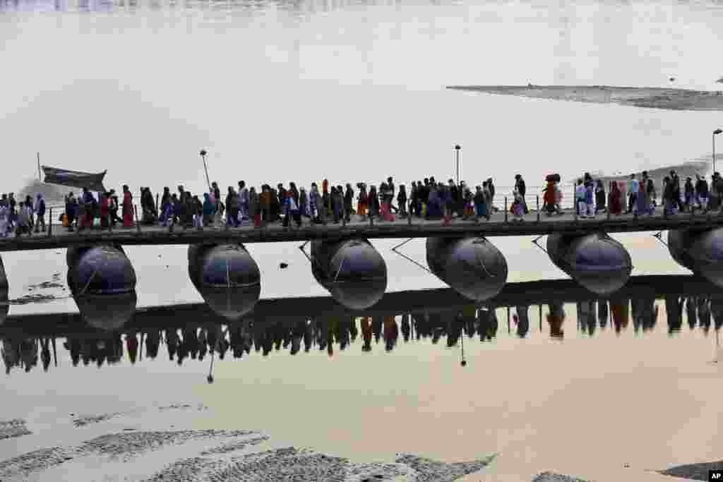 Indian Hindu devotees walk across a pontoon bridge at the Sangam, the confluence of the Ganges, Yamuna and the mythical Saraswati, on the eve of &ldquo;Mauni Amavasya&rdquo; or new moon day, considered the most auspicious date of bathing during the annual month-long Hindu religious fair &ldquo;Magh Mela&rdquo; in Allahabad.