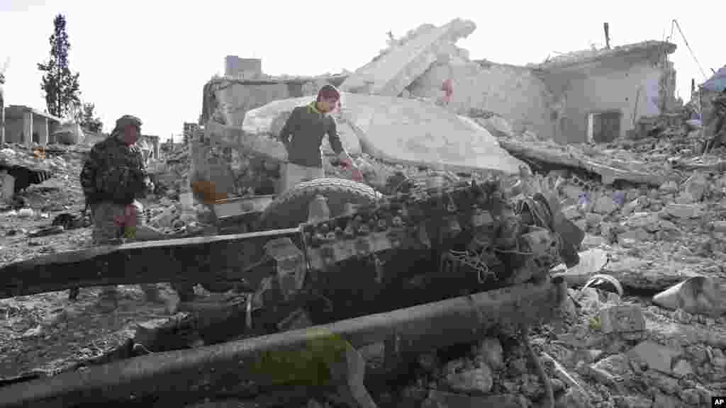 Des combattants kurdes montrent les dommages causés par un camion piégé dans Kobani, le 19 novembre 2014.